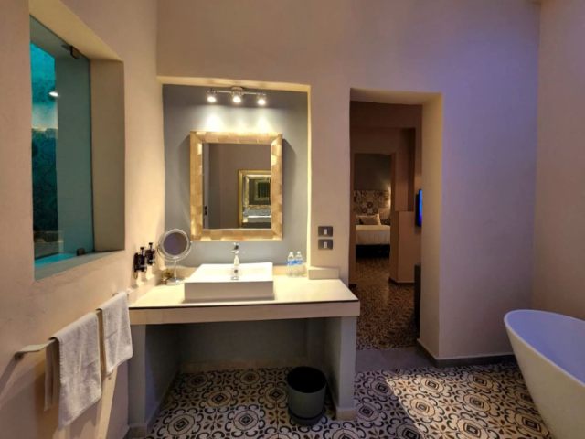 "Cozy bathroom with a bathtub and sink, viewed through an open door into the adjoining room."