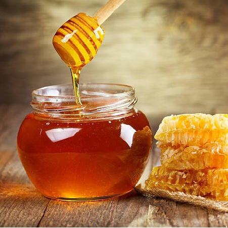 “Golden Yucatán honey served in a small jar, surrounded by tropical breakfast ítems.”