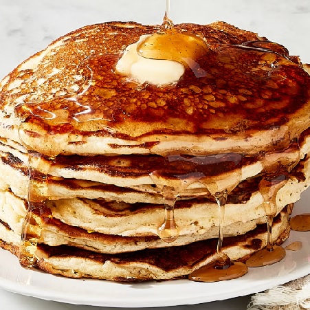 “Golden pancakes topped with melting butter and drizzled with maple syrup.”