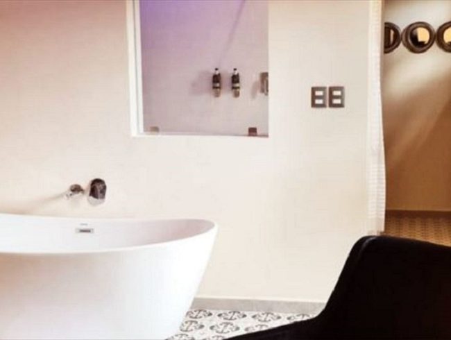 “Open-concept bathroom with a tow people bathtub and shower overlooking the adjoining room.”