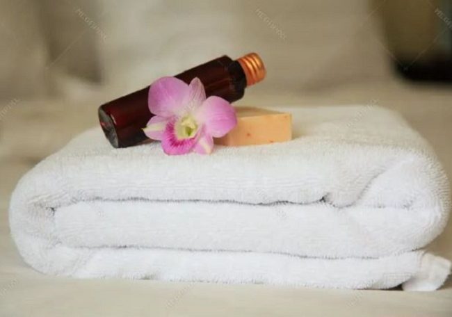“Fresh towels and travel-size shampoo placed in a hotel room.”