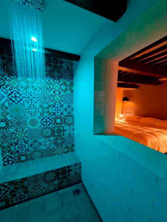 "Chromotherapy shower with glass wall view into boutique room at Acqua In Bocca Mérida"